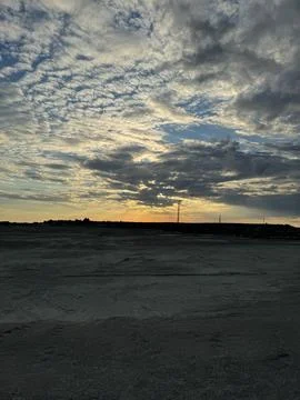 Vast barren landscape under a dramatic sunset sky Stock Photos