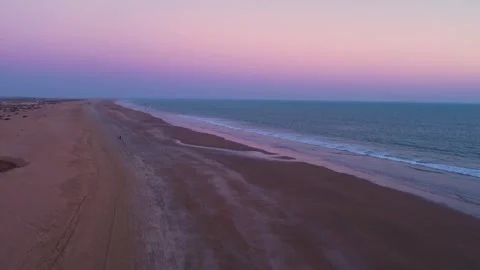 Vast beach with a purple sunset sky with paraglider moving away Stock Footage 261828034