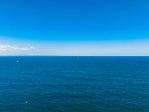 Vast blue ocean view with a distant ship under clear sky Stock-Fotos