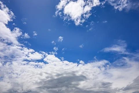 Vast blue sky with soft white clouds drifting gently Stock Photos