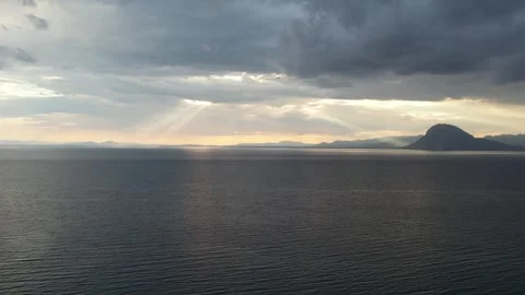Vast calm sea beneath dramatic clouds and sun rays at dusk horizon Stock Footage 343944518