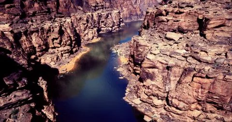 Vast canyon landscape features a winding river nestled between rocky cliffs Stock Illustration