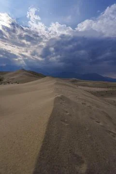 Vast desert dunes under a dramatic sky with sunbeams Stock Photos