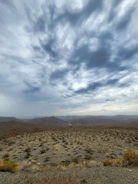 A vast desert landscape under a dramatic cloudy sky. Stock Photos