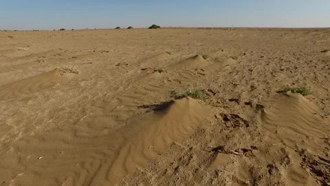 In the vast desert a lone tractor drags a cart across, stock footage. Stock Footage 304816985