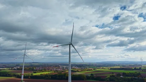 Vast fields and tall wind turbines stand proudly against a dramatic sky filled Stock Footage 320079172