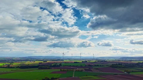 Vast green fields and wind turbines stretch under a dynamic sky of clouds and Stock Footage 320079630