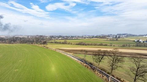 Vast Green Fields With Distant Towns and a Cloudy Blue Sky in Rural Landsca.. Stock Photos