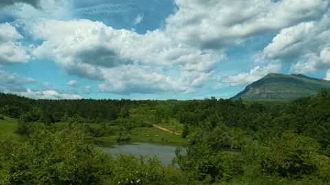 Vast green hills roll beneath a bright blue sky. Vrmdza Lake, Serbia Vídeos de archivo 338025332
