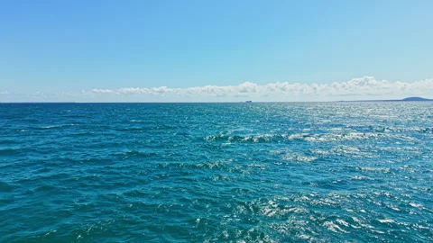 Vast ocean view under clear sky with light waves and distant ship on horizon Stock Footage 342332842