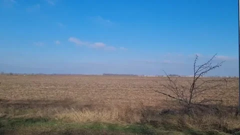 Vast open field with dry soil under a clear blue sky Stock Footage 302101189