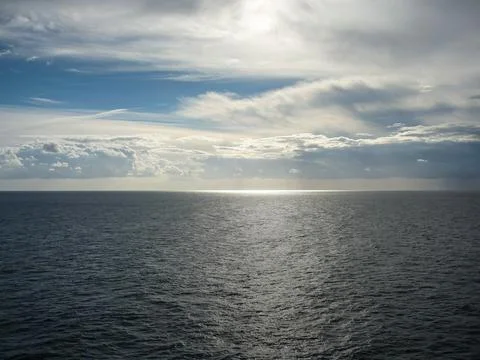 Vast open sea under dramatic clouds with sunlight breaking through Stock Photos
