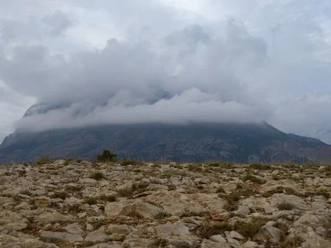 Vast rocky height crowned with cloud, Remote mountain massif with dramatic .. 库存照片