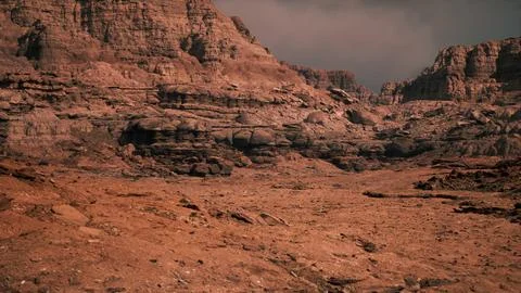 Vast rocky landscape with dramatic cliffs under a cloudy sky at dusk Stock Illustration