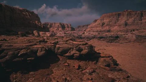 Vast rocky landscape with towering cliffs under a cloudy sky in daylight Stock Illustration