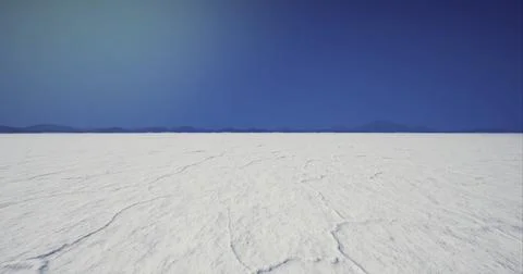Vast salt flat landscape under a clear blue sky with distant mountains Stock Illustration