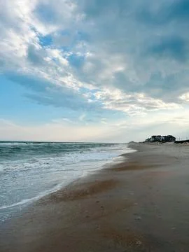 Vast sandy beach with ocean waves and a dramatic cloudy sky 写真素材