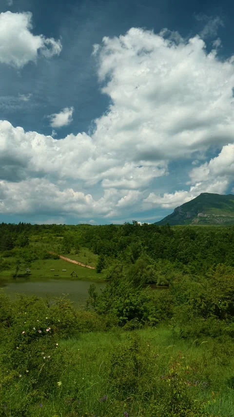 Vast sky with puffy clouds above green hills. Vrmdza Lake, Serbia. Vertical Stock Footage 338029898