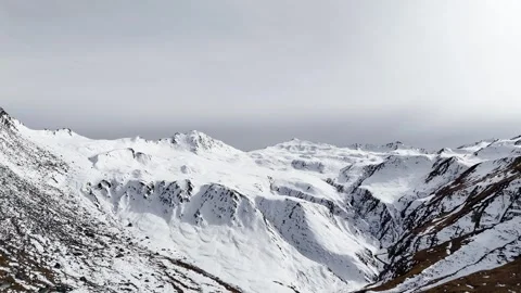Vast snow covered mountain range spreads beneath pale gray winter sky showing Vídeos de archivo 343677444