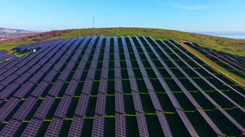 Vast solar panel array harnesses sun's energy on a sunny hillside in early Stock Footage 331890199