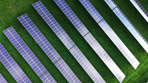 Vast solar panels spread across green fields from high above Stock Footage 325087596