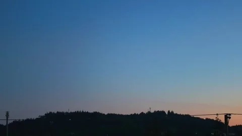 Vast twilight gradient sky background over silhouetted forest hill horizon Stock Footage 346804222