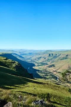Vast verdant valley beneath clear azure sky with distant ridges 스톡 사진