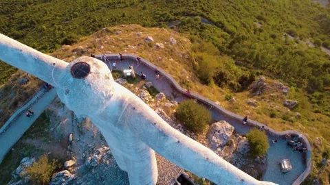 Vast View of a Giant Statue Overlooking the Landscape at Sunset With Visitors Stock Footage 318387503