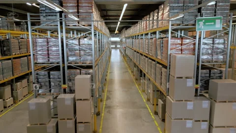 A vast warehouse filled with large wrapped packages and metal racks. 库存影片 307999793