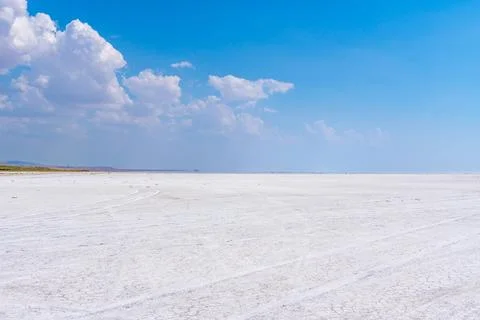 Vast white salt flat under a clear blue sky with scattered clouds. Turkey Stock Photos