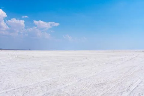 Vast white salt flat under a clear blue sky with scattered clouds. Turkey Фото
