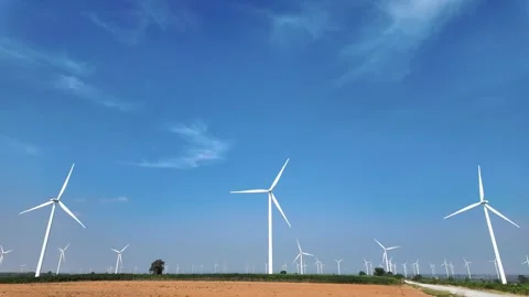 Vast wind farm with multiple turbines spinning under a clear blue sky. 動画素材 301767165