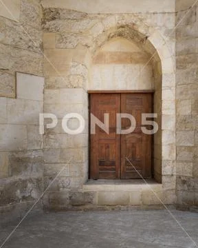 Vaulted closed decorated wooden grunge door in bricks stone wall Stock Photos