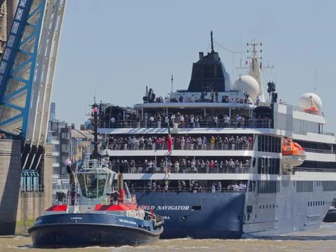 VB Boluman Tug Pulls World Navigator Cruise Ship in Reverse Beneath Tower B.. Stock Photos