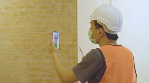 VDO conference by phone with engineer and engineer checking wall Stock Footage 132801099