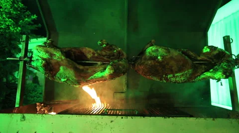 Veal carcass roasting on a rotating spit, with charcoal and flame at outdoor. Stock Footage 63544844