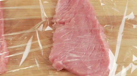 Veal escalopes being tenderised between layers of clingfilm Stock Footage 24636774