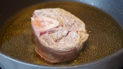 Veal meat with marrow bone breaded in flour is fried in a pan Stock Footage 94718086