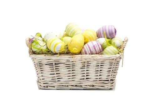 Vector wicker basket sitting on white bg with straw, pastel striped dotted eggs Foto stock