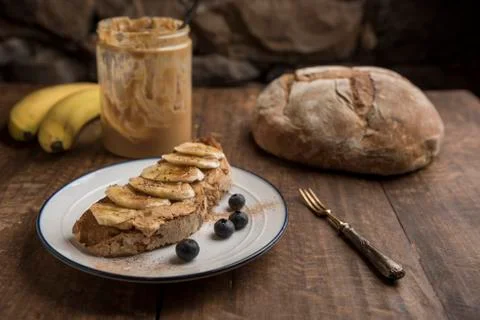 Vegan breakfast with toasted rustic bread with peanut butter and banana Stock Photos