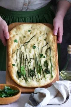Vegan focaccia made from yeast dough with various herbs held by a woman. Rust Stock Photos