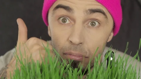 Vegan guy in a bright hat eats green grass Stock Footage 87981364