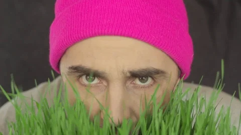 The vegan guy in a bright hat eats green grass Stock Footage 87981390