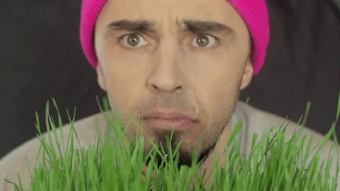The vegan guy in a bright hat eats green grass Stock Footage 87981421