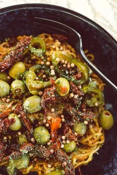 Vegan spicy noodles topped with olives sundried tomates japlapenos and corian Stock Photos