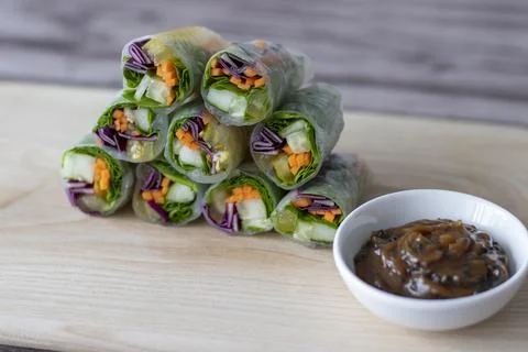 Vegan vegetable spring rolls in rice paper on a board with peanut paste, soy Stock Photos