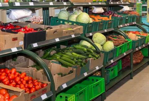 Vegetable counter in the store, boxes of cucumbers, tomatoes, cabbage, carrot Foto stock