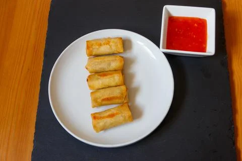Vegetable filled thai spring rolls and sweet chili sauce on a table. Top view Stock Photos
