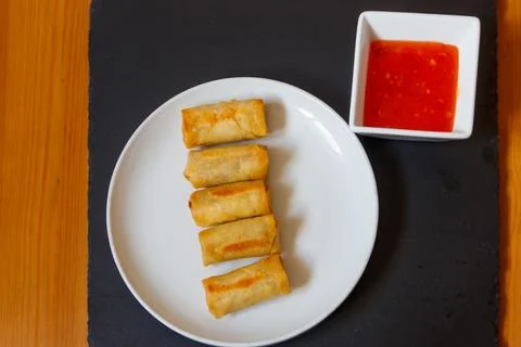 Vegetable filled thai spring rolls and sweet chili sauce on a table. Top view Stock Photos
