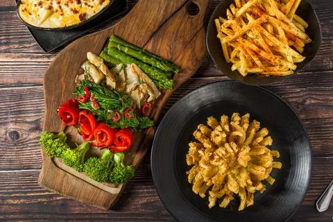 Vegetable main course plate with onion flower broccoli and fries Stock Photos